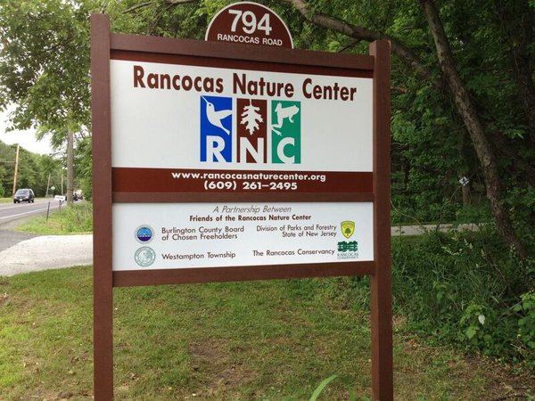 The Rancocas Nature Center's wooden entrance sign at 794 Rancocas Road, with trees behind