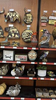 Gas-station shelves of bear, elk and Montana signs, with rooster, eagle and wolf statues and a rooster front and center
